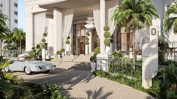 A blue vintage car sits outside a hotel entrance.