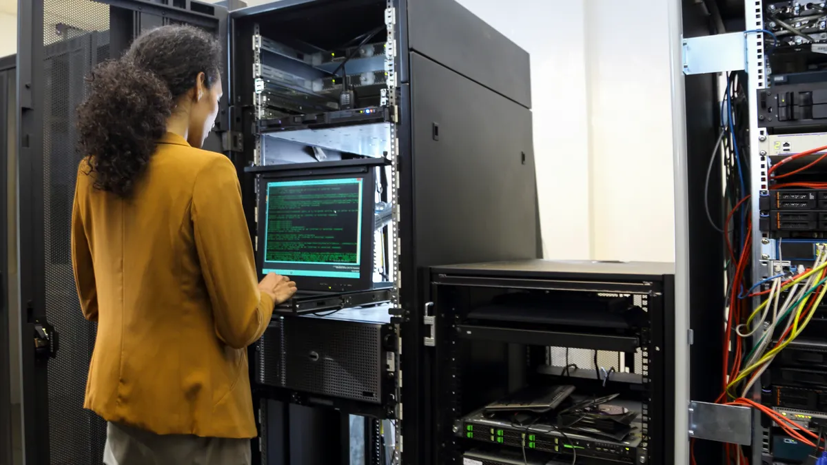 a tech worker reboots a server rack using a laptop