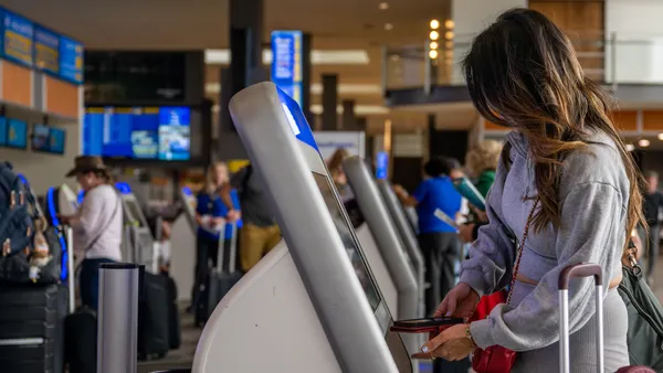 A passenger checks-in for their flight at an airport kiosk.