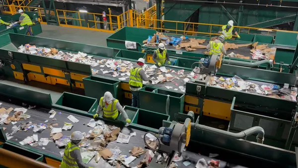 Workers sort recycling by hand on a conveyor belt