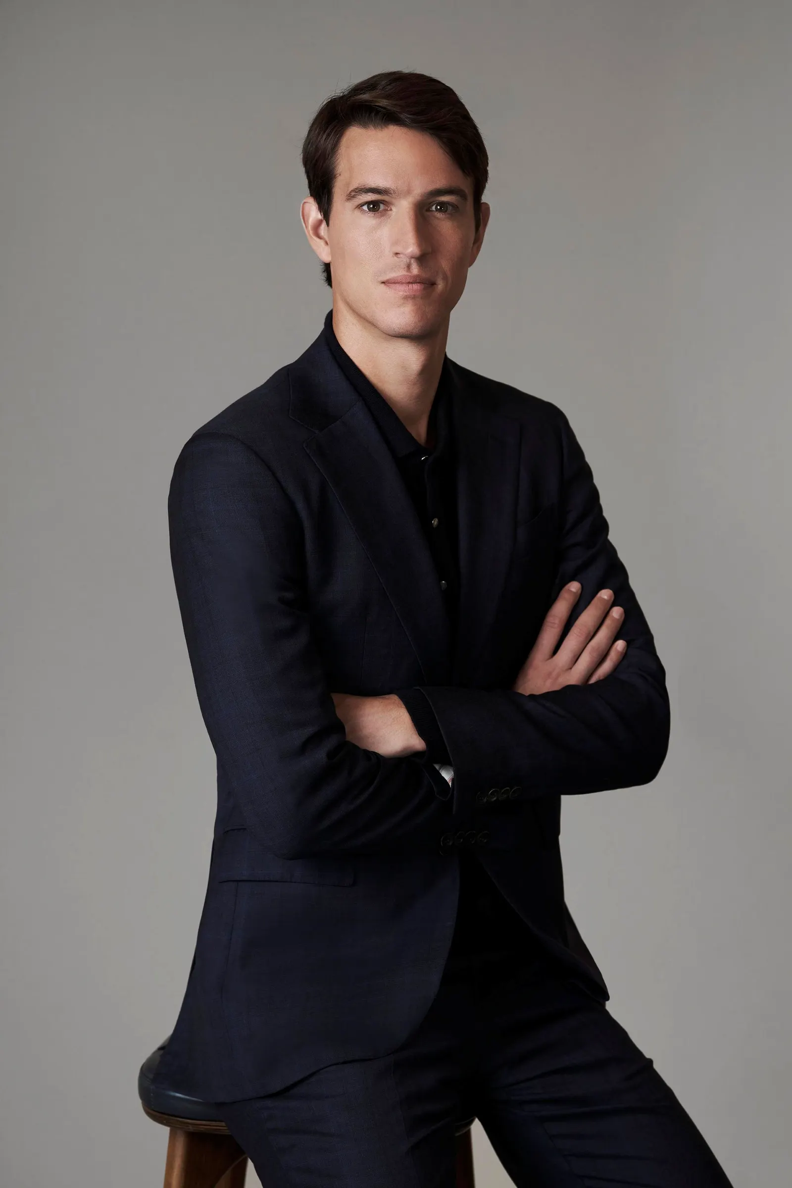 A headshot of Alexandre Arnault in a black suit against a grey background.