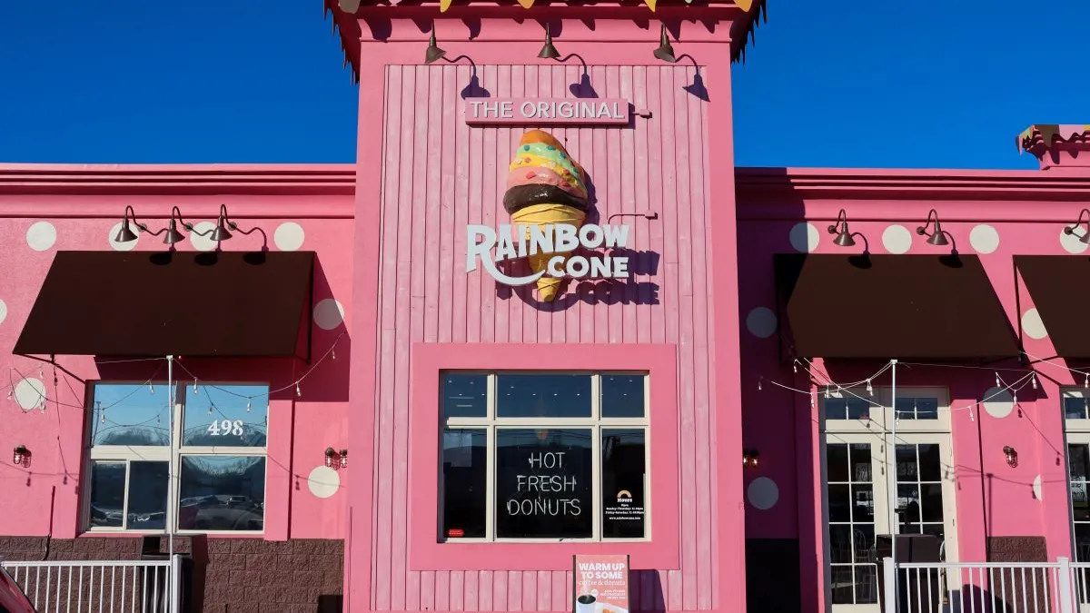 A photograph of a pink building with white polka dots with a sign that says "The Original Rainbow Cone."