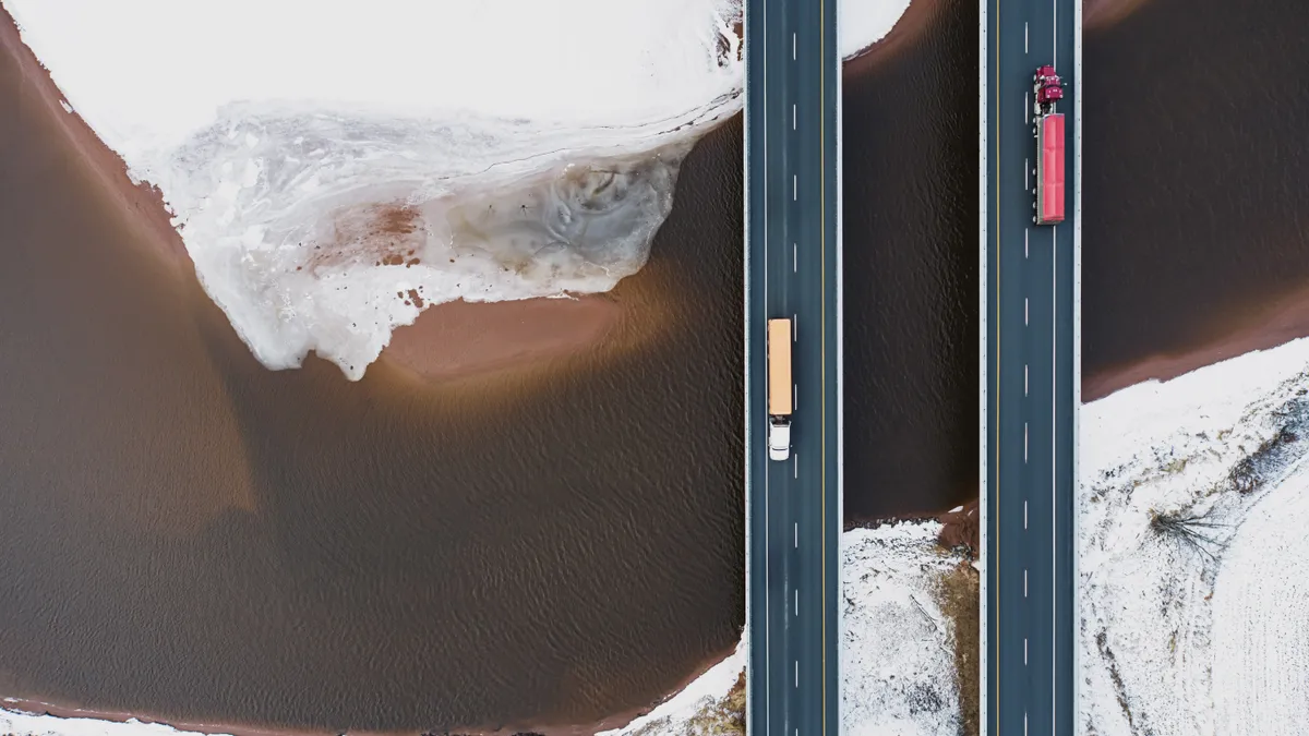 Aerial drone view of semi trucks crossing a tidal river.