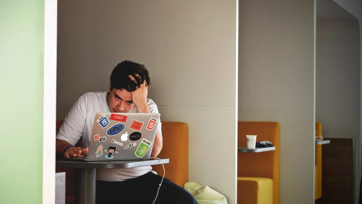 Man in white shirt using a MacBook Pro