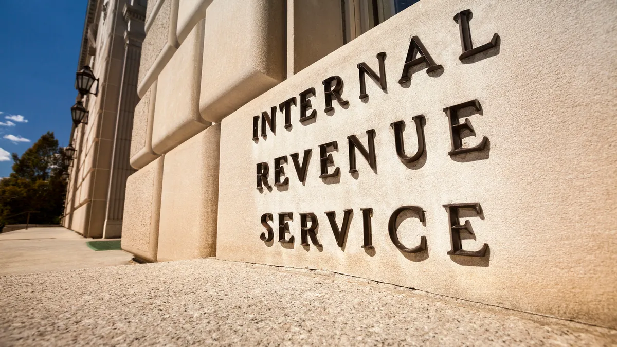 The Internal Revenue Service sign in capital letters on a tan building on a sunny day.