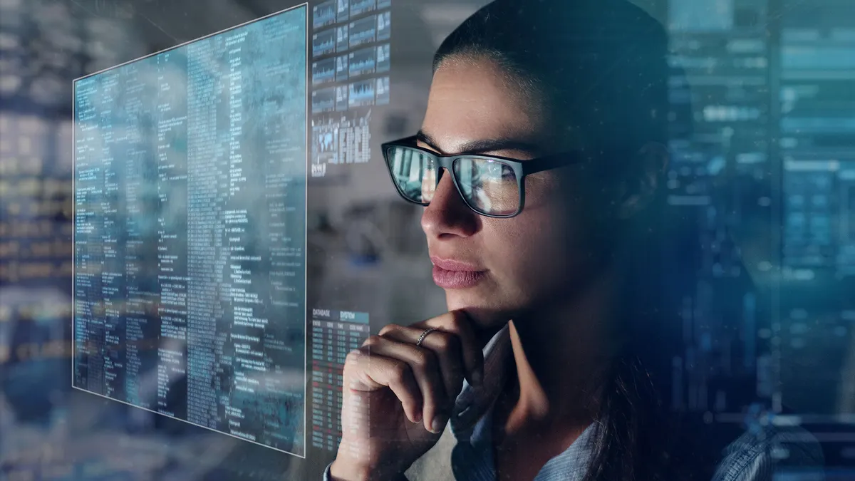 woman with glasses looking at a screen with data points