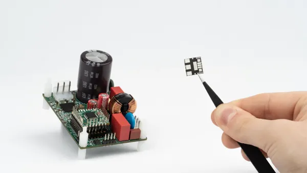 Hand holding a semiconductor with a pair of tweasers