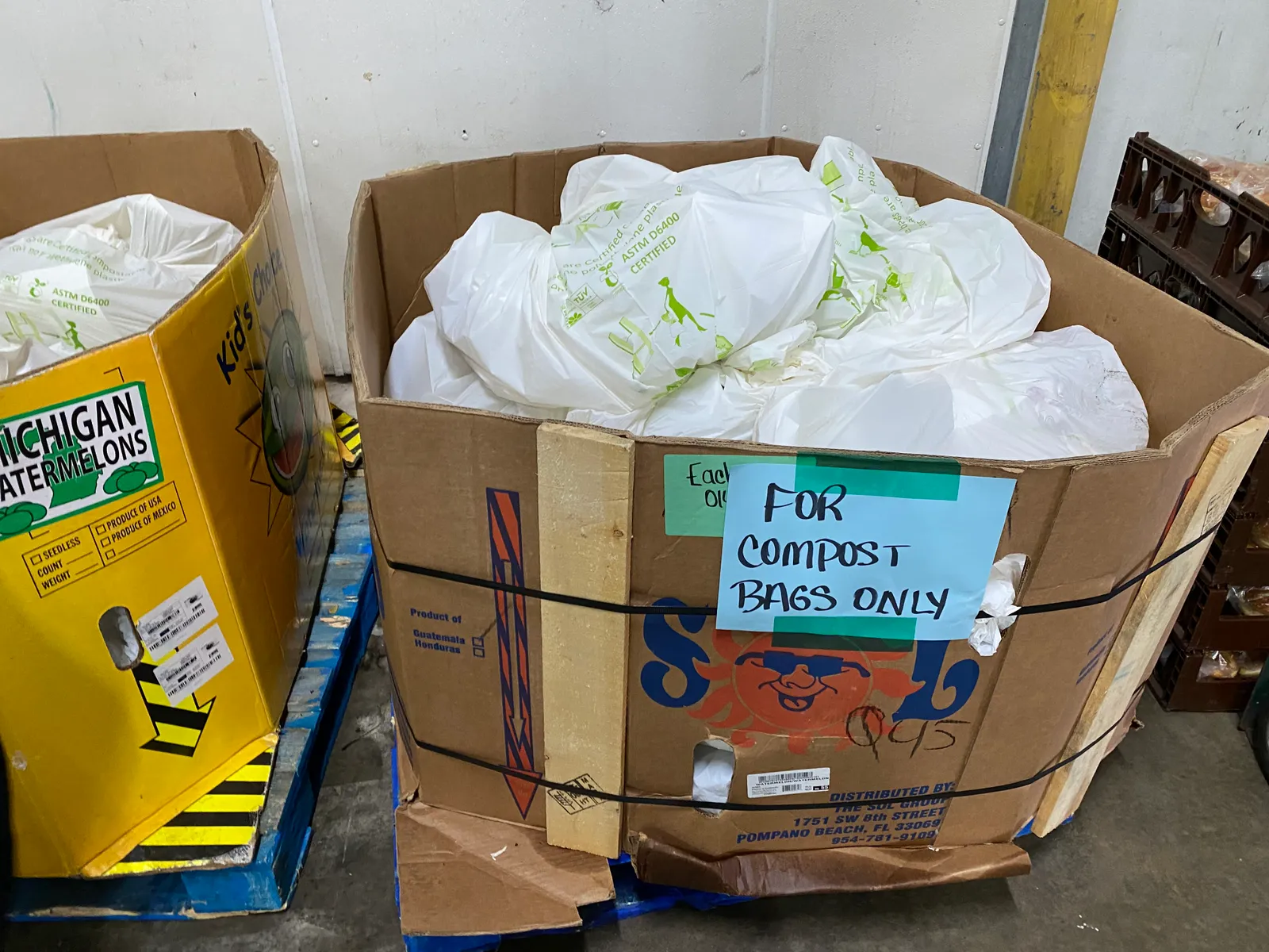 Large cardboard box on pallet with full white bags piled inside.