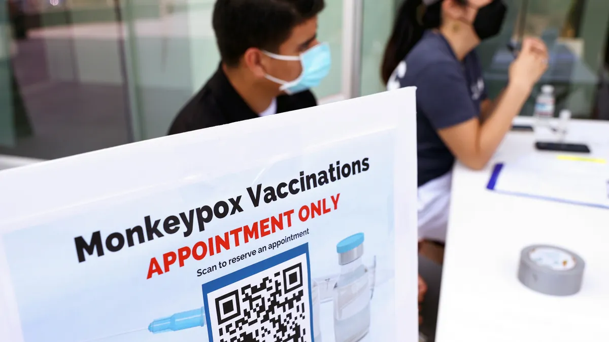 Health workers sit at a check-in table at a pop-up monkeypox vaccination clinic which opened by the Los Angeles County Department of Public Health.