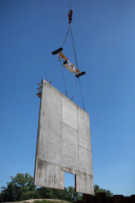 A load stabilizer on the end of a crane holds a large piece of formwork steady.