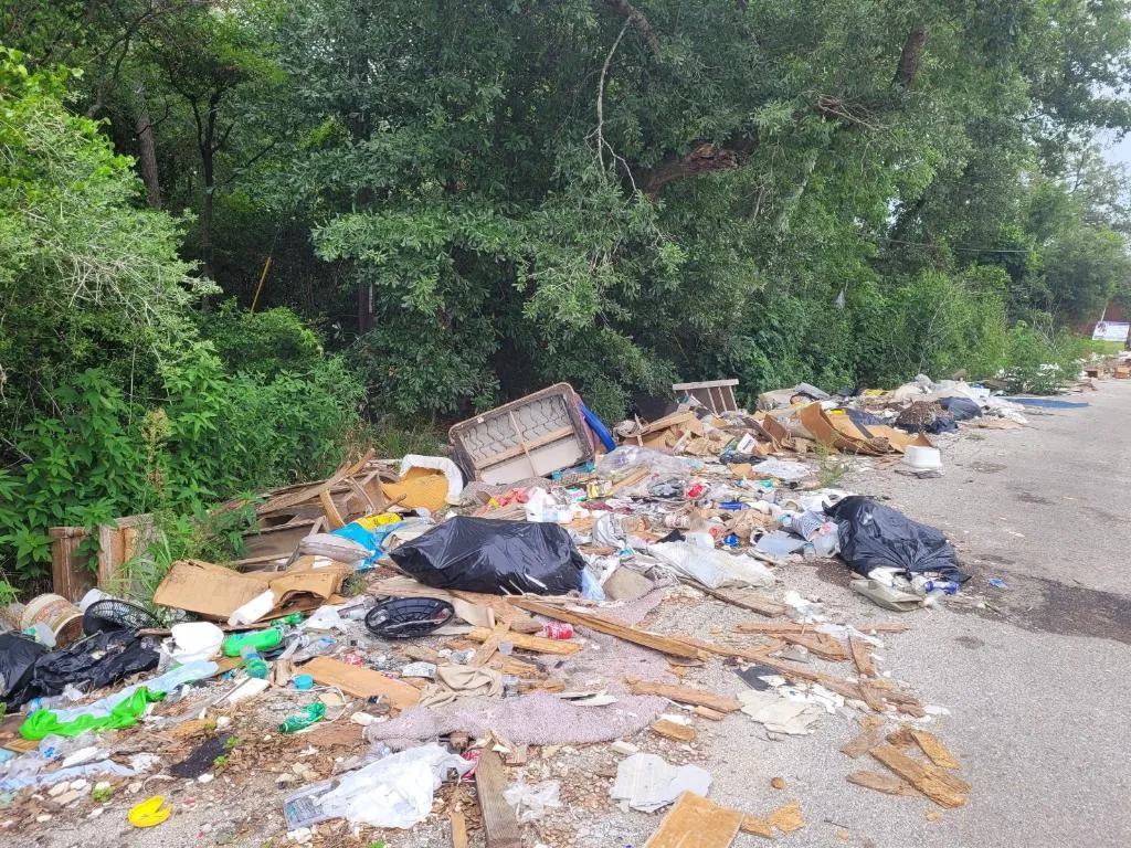 A street littered with household trash and old furniture