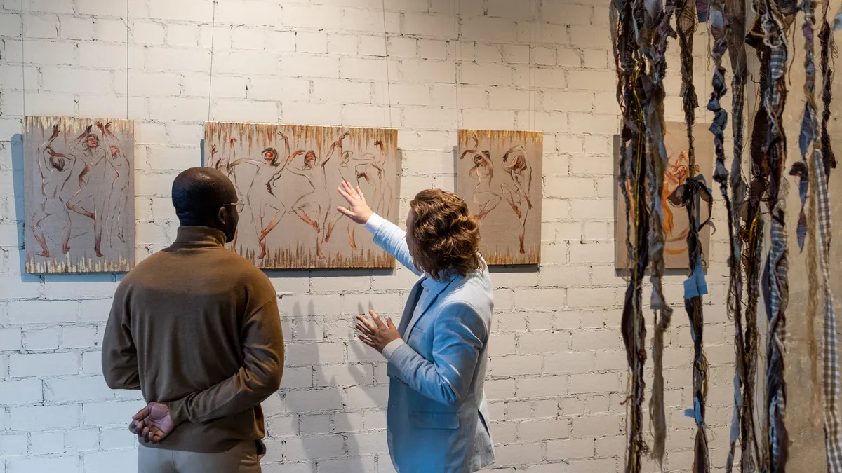 A contemporary artist guides a museum visitor through exhibits at an art gallery.