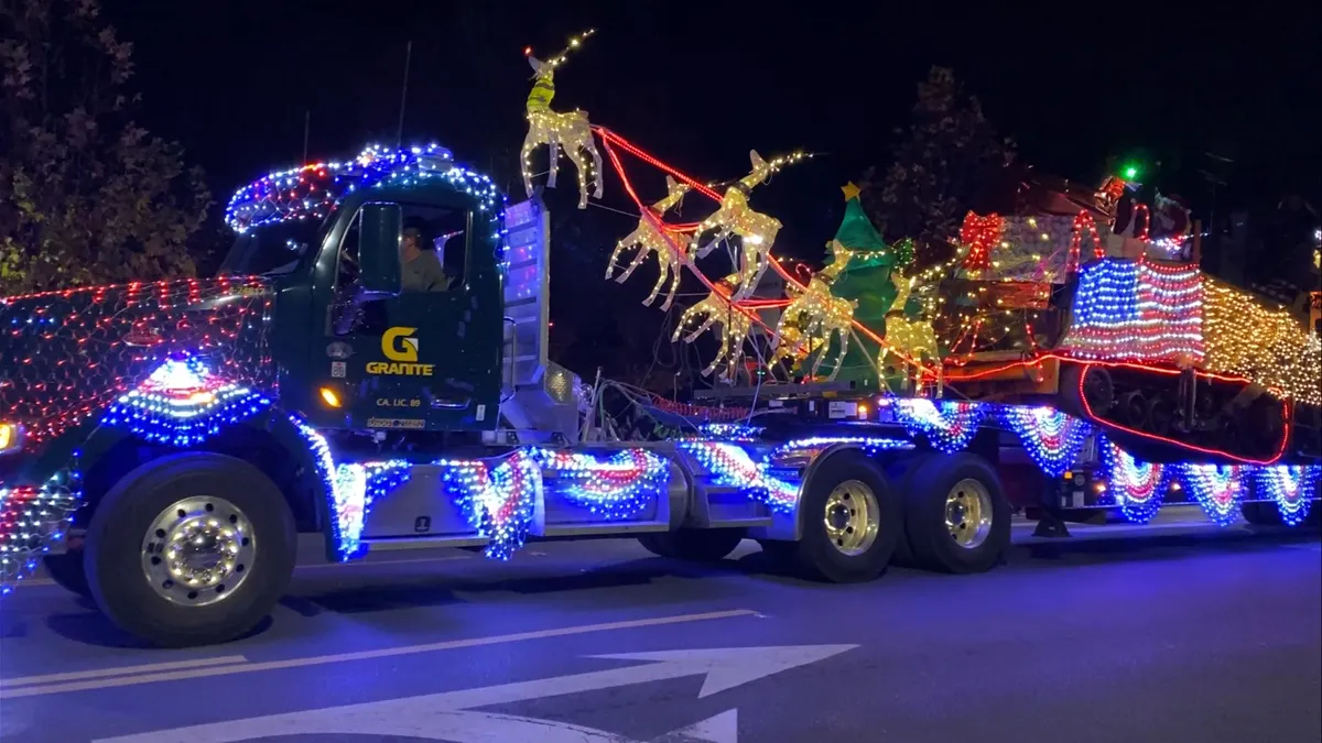 A person drives a truck emblazoned with Granite Construction's logo, hauling Christmas paraphernalia on the back.