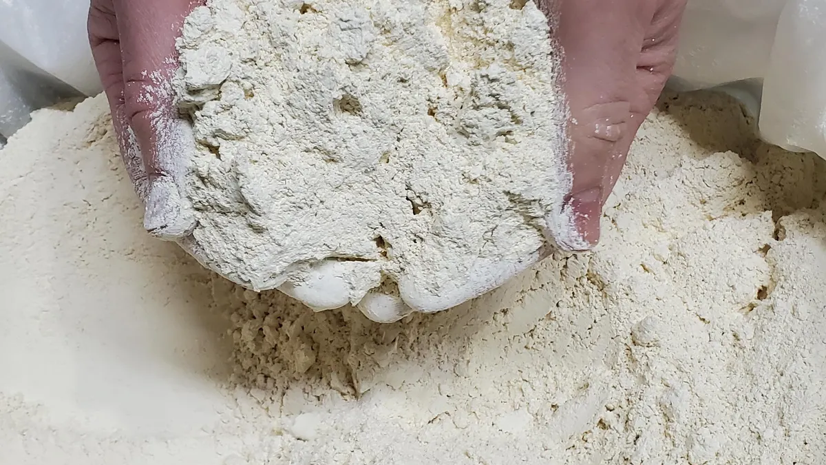 Hands hold white protein powder made by Superbrewed Food.