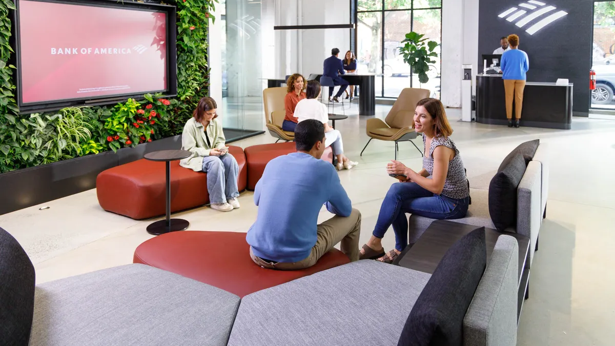 customers sit and talk or play on their cell phones in a bank of america financial center lobby