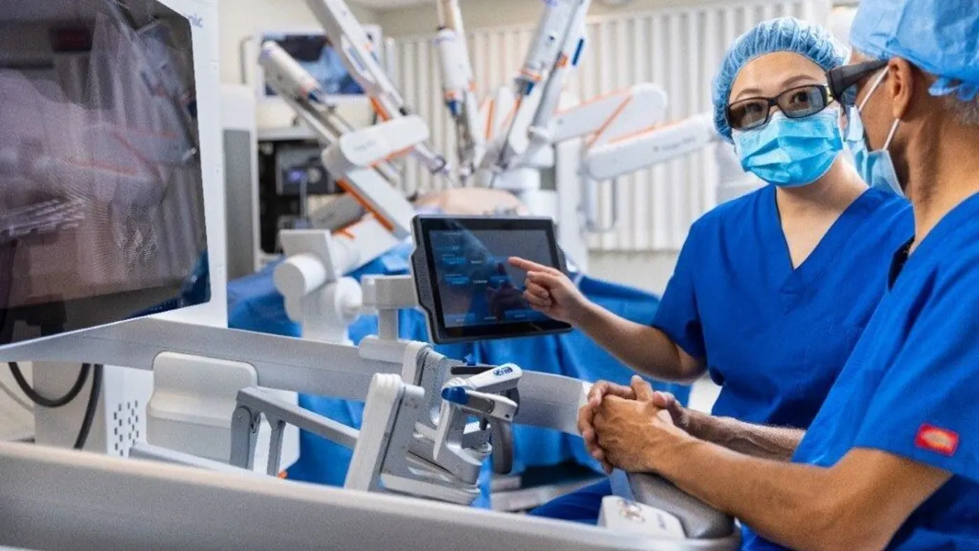 Two people view Medtronic's Hugo robotic surgery system in an operating room.