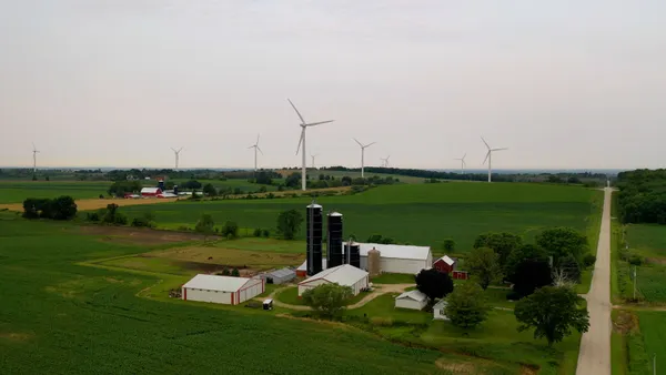 Wind turbines stand near a farm.