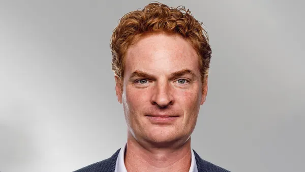 Immunic CEO Erik Lundgren faces the camera in a dark blazer and light-colored shirt against a plain gray background.