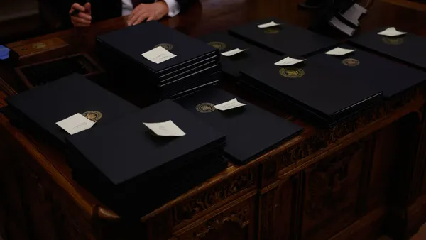 A huge array of executive orders sit on the table, with sticky notes atop them