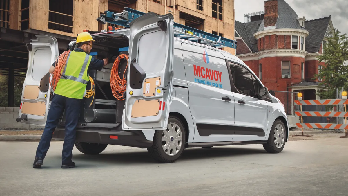 A construction worker accesses the rear of a 2021 Ford Transit Connect.