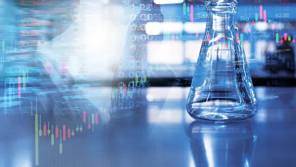 A double exposure image of a glass flask in a laboratory with stock market information in the background.