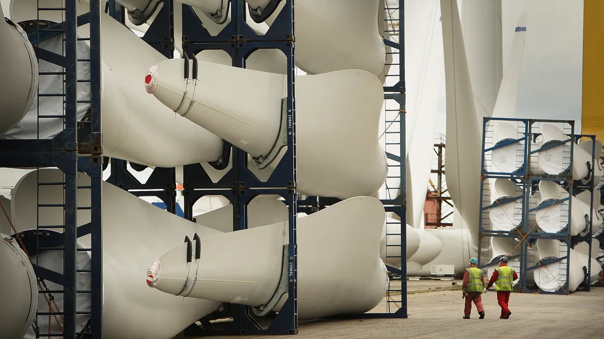 Workers pass stored wind turbine blades at the Harland & Wolff shipyard n Belfast, Northern Ireland.