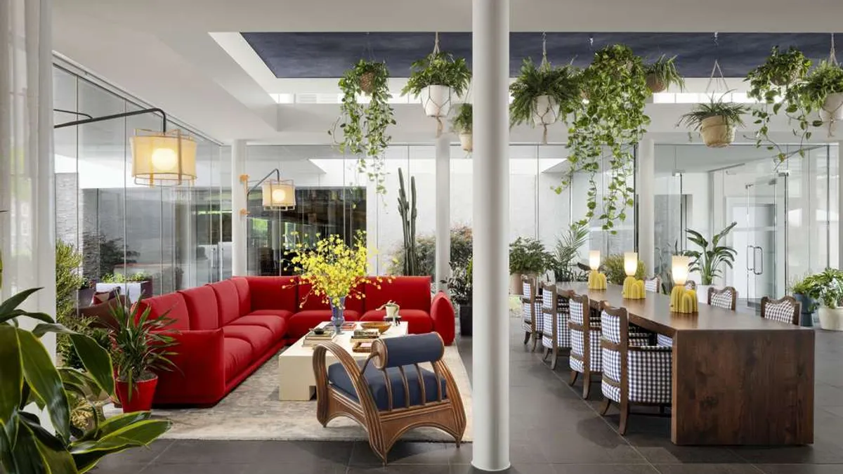 A lounge area includes a red sofa and a long wooden table.