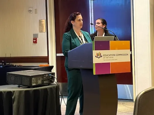 Two people are standing behind a podium in a room.