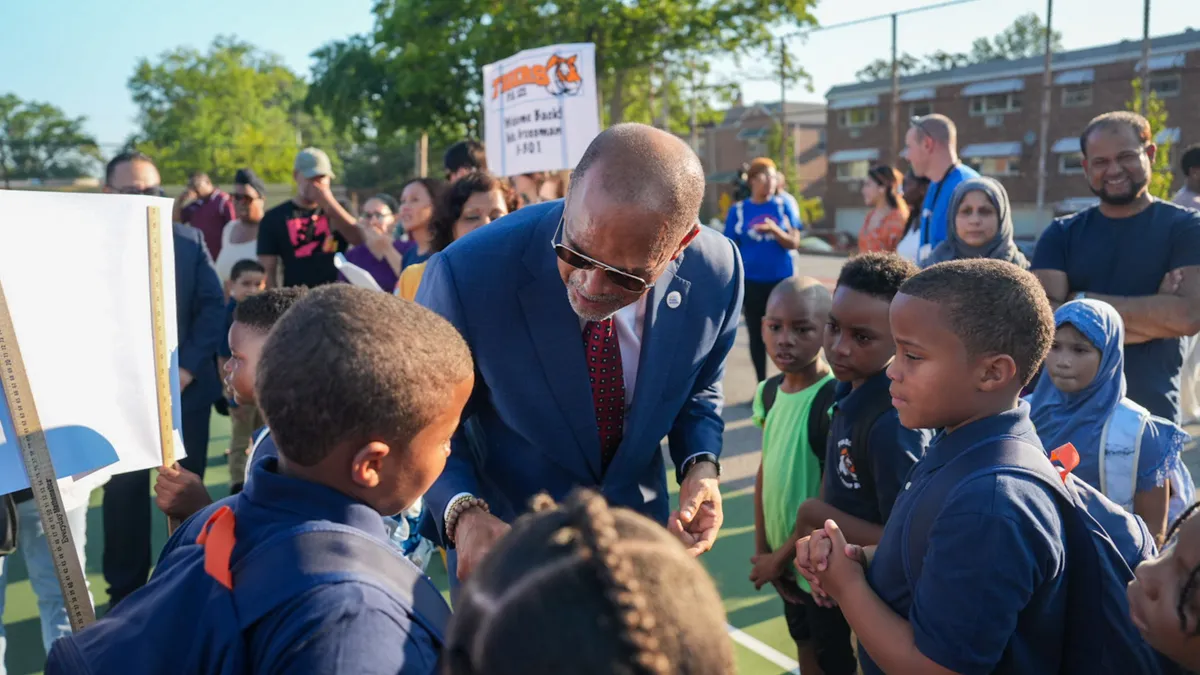 New York City Schools Chancellor David Banks bends down to greet students