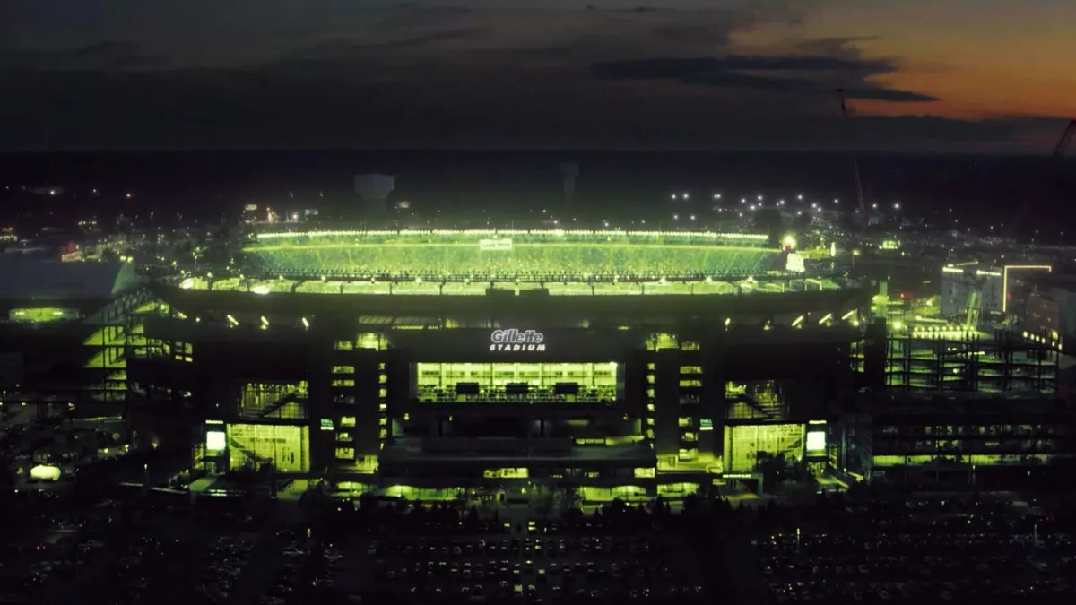 Gillette stadium glows green at night.