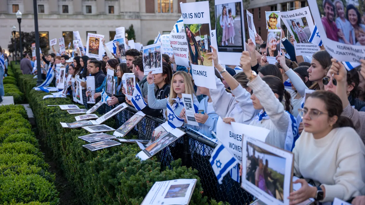 A row of protesters at Columbia University, each holding an identical sign.