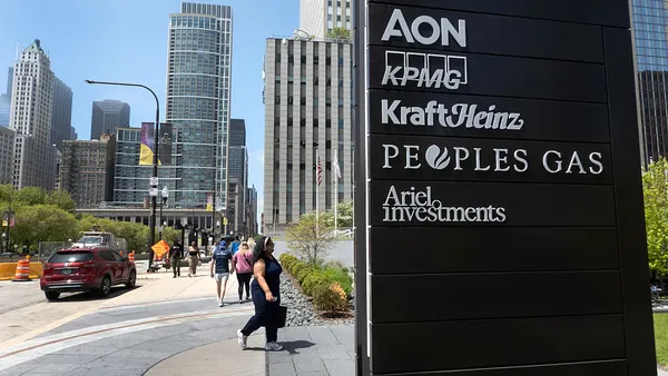 A view of downtown Chicago appears on the left while a black sign listing businesses, including Aon, appears closely in the foreground on the right.