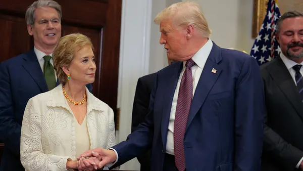 Education Secretary Linda McMahon and President Donald Trump clasp hands as they speak to each other