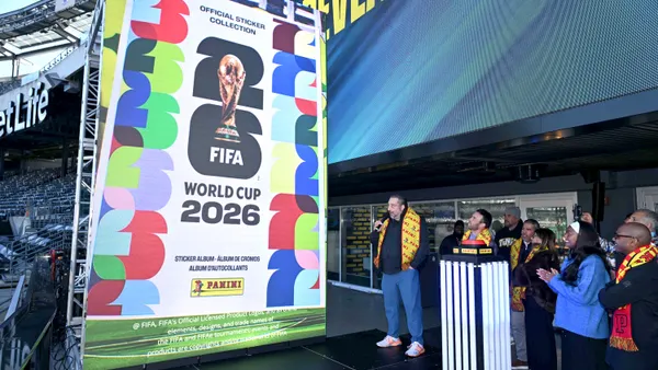 A colorful sign reads "Official Sticker Collection, World Cup 2026" in a sports stadium.