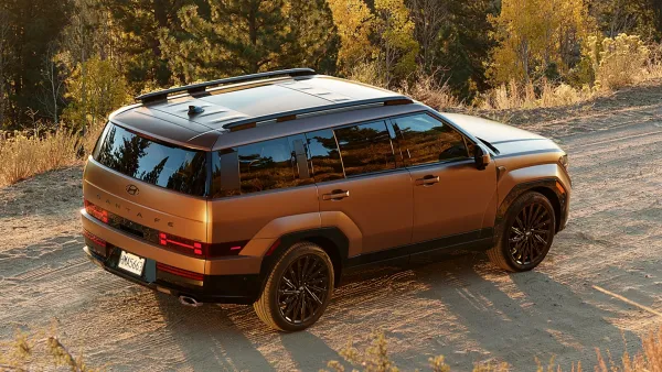 The 2024 Hyundai Santa Fe SUV on a dirt road with tress in the background.