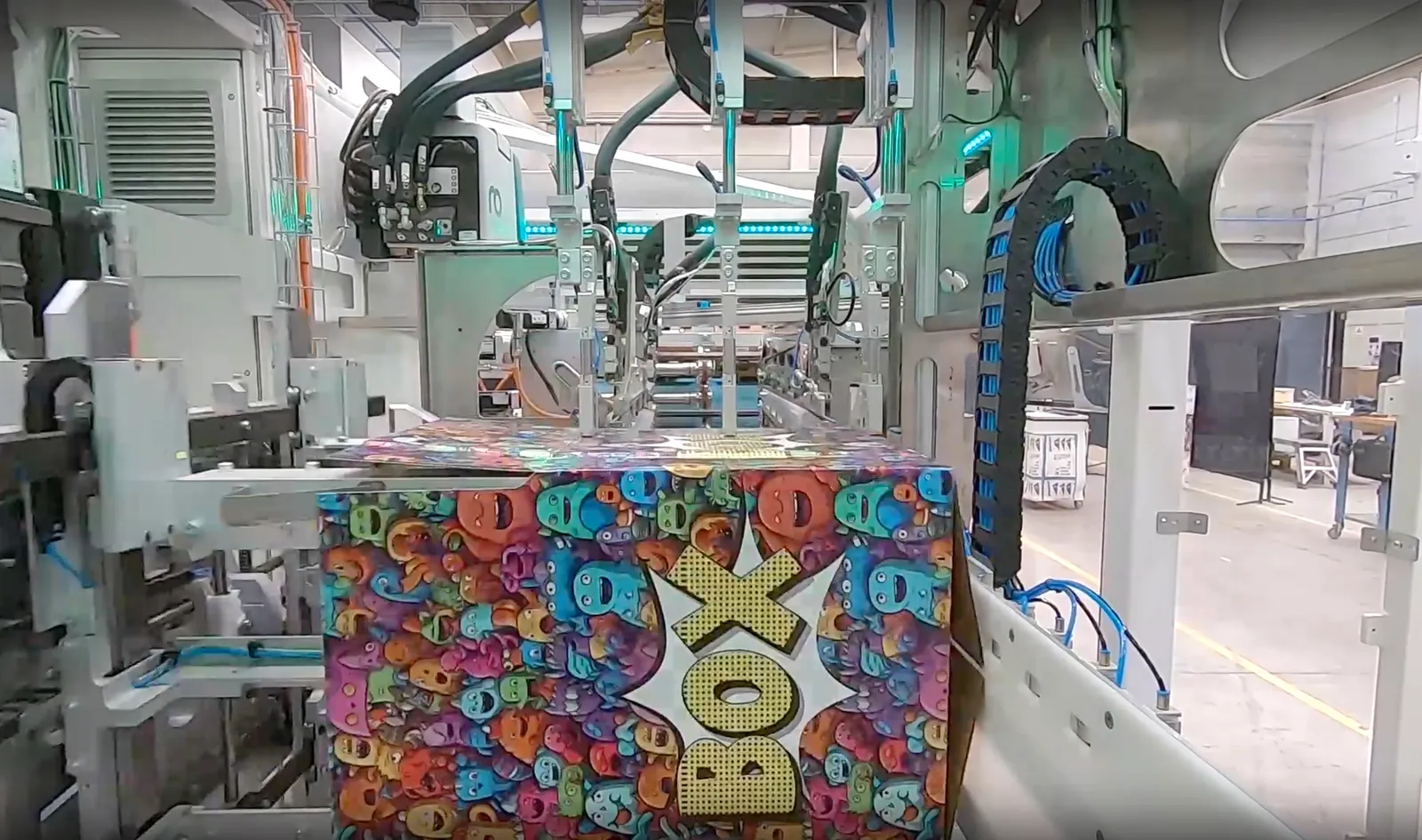 A colorfully printed box gets folded on an industrial machine.