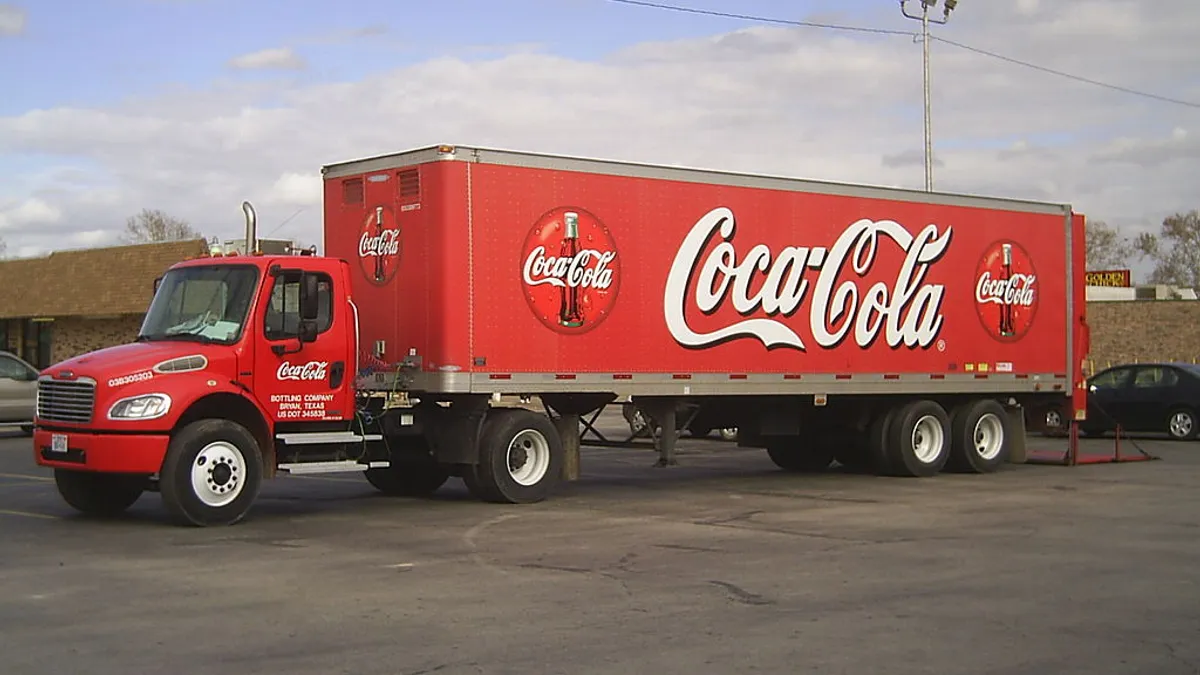 A coca-cola truck parked in a parking lot.