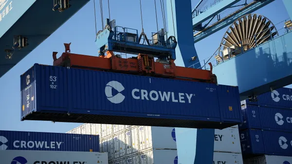 A 53-foot blue container being moved by a gantry crane.