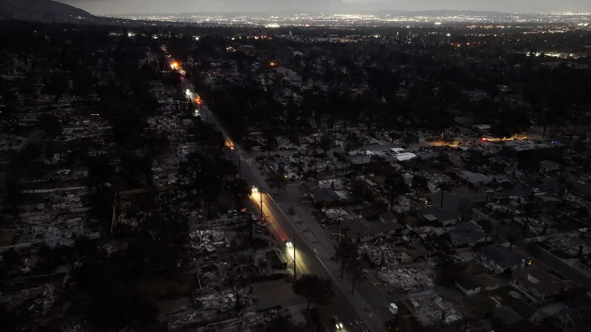 An aerial view of a line of cars with their headlights on driving through a darkened valley