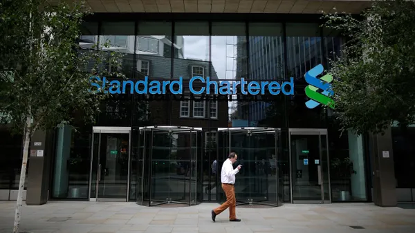 A man smokes outside a Standard Chartered bank location.