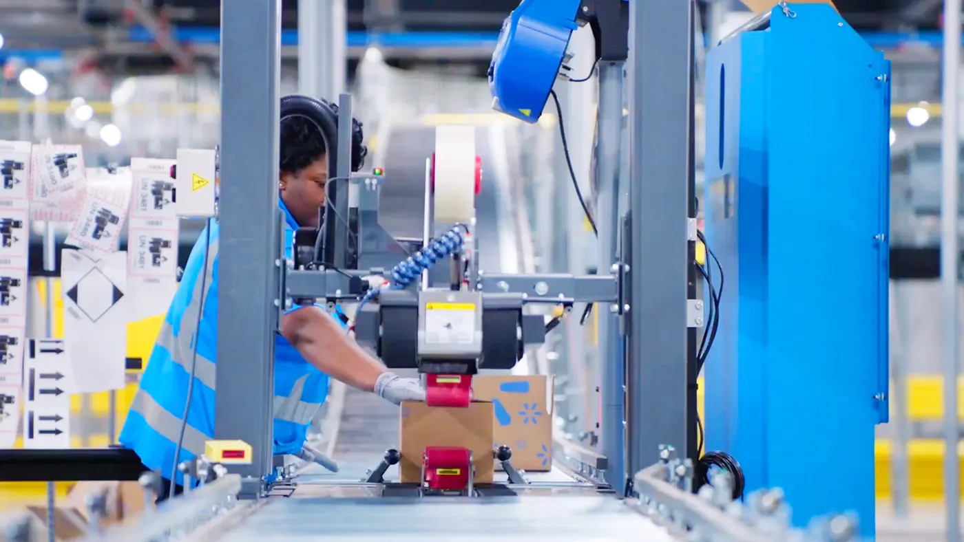 A person places their hand on a package moving along a conveyor belt.