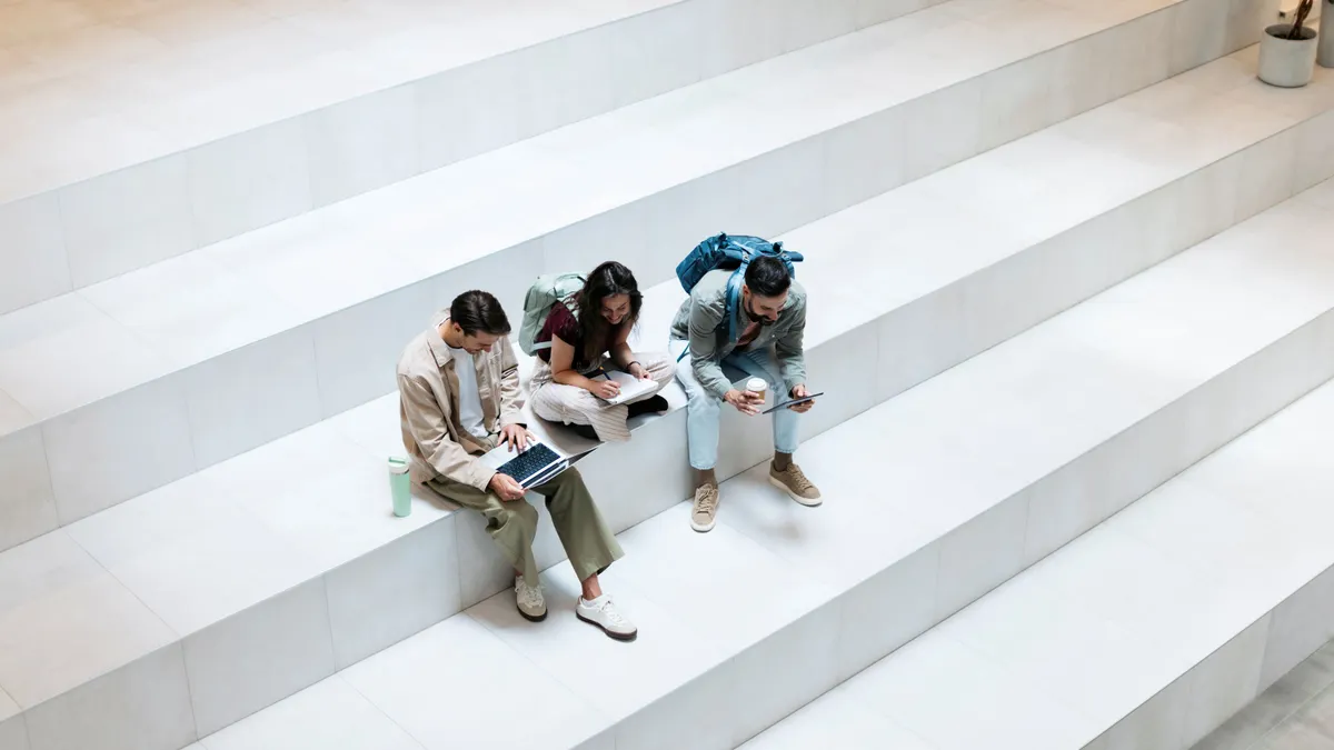 College students sit on a staircase working.