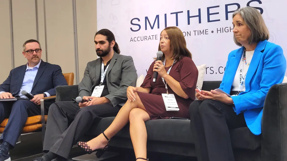 Four people on a stage speaking at a conference.