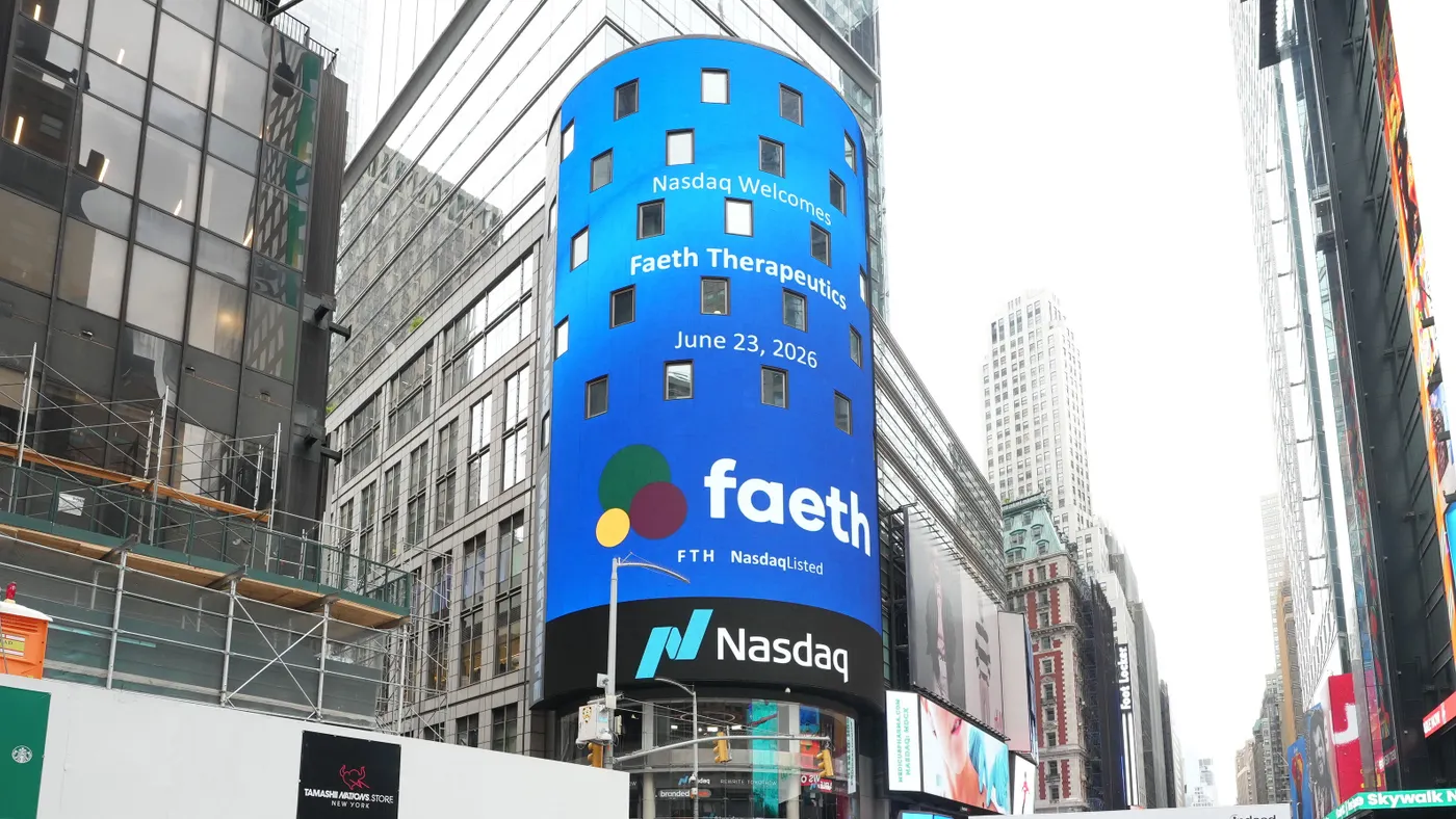 A low-angle, full shot of the Nasdaq MarketSite building in Times Square under a bright, overcast sky, featuring a large, curved blue digital billboard. The billboard displays a welcome message reading "Nasdaq Welcomes Faeth Therapeutics, June 23, 2026," alongside the Faeth logo and "FTH Nasdaq Listed."