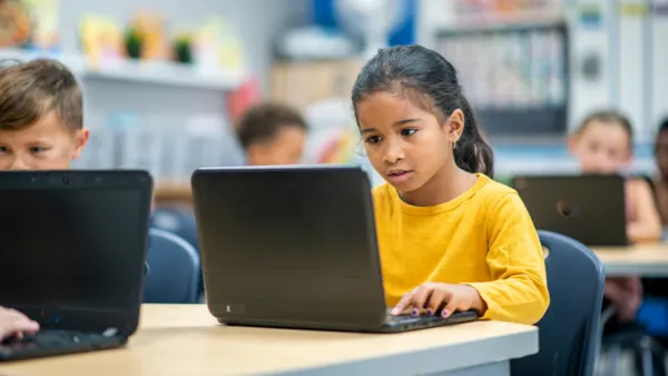 A student working on their laptop in a classroom.