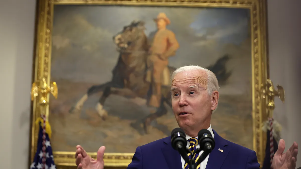 President Joe Biden stands in front of a painting.