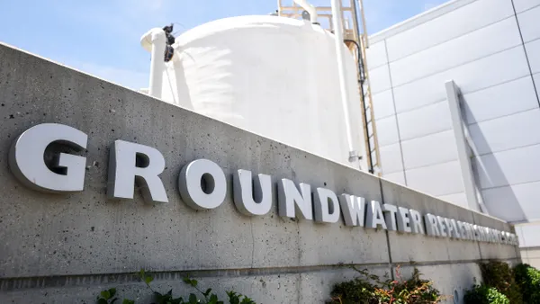A concrete building with the words "GROUNDWATER REPLENISHMENT" on it and a white tank in the background.