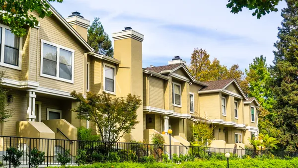 A set of attached homes with yellow siding.