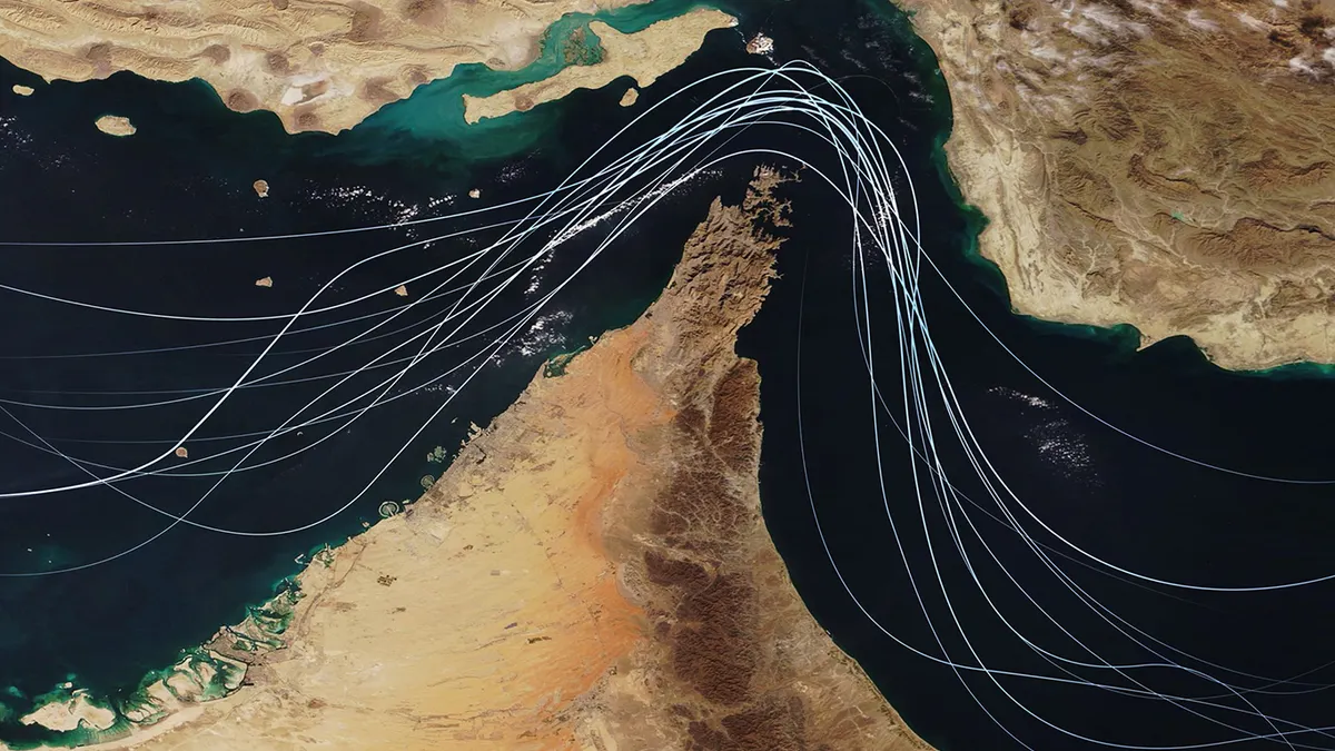 Satellite view of the Strait of Hormuz with white graphic lines representing global shipping lanes and maritime traffic between the Persian Gulf and Gulf of Oman.