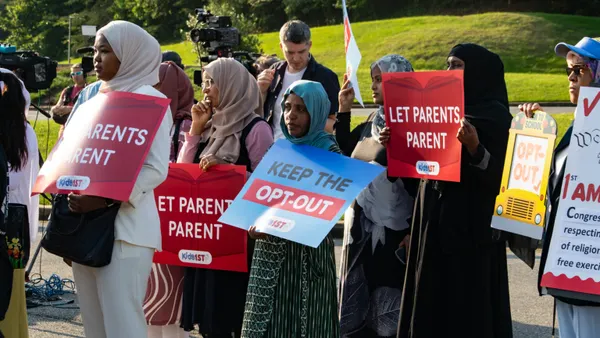 Women wearing hijab hold protest signs